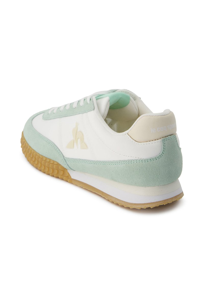 Zapatilla con una parte superior de cuero blanco y detalles en ante verde menta, suela de goma texturizada y un logo en el lateral y en el talón.