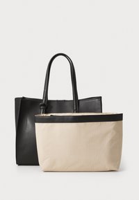 Zwarte leren tote bag met een gestructureerd ontwerp, gecombineerd met een beige gestreepte canvas tas met zwarte accentrand en handvatten.