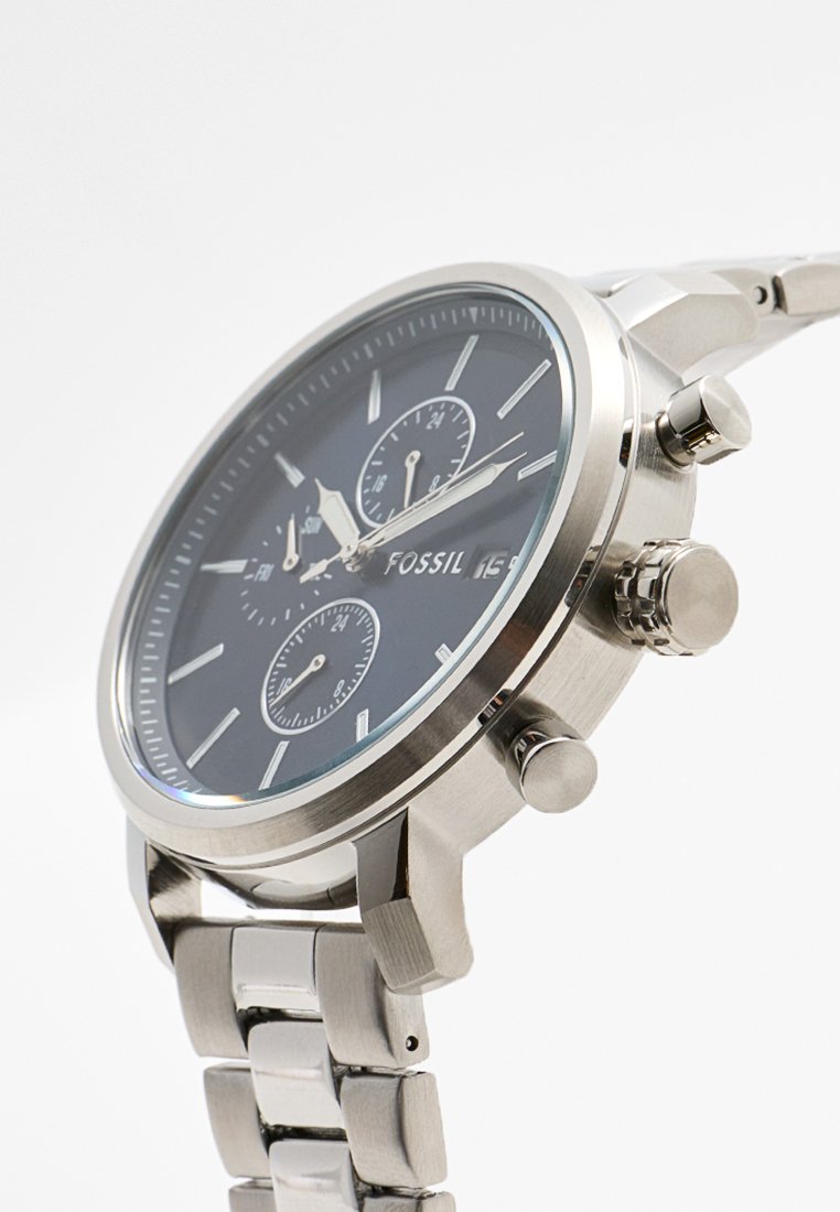 Montre en acier inoxydable argenté avec un cadran noir, trois sous-cadrans de chronographe, des marqueurs lumineux et un bracelet poli. Bouchette ajustable.
