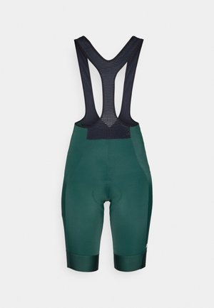 Shorts de cyclisme verts avec des bretelles noires en mesh, zone rembourrée au niveau de l'assise et un élastique en bas pour un ajustement parfait.