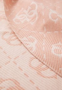 Pink textile with a ribbed texture featuring a subtle pattern. The fabric is soft, with a folded edge revealing a lighter shade.
