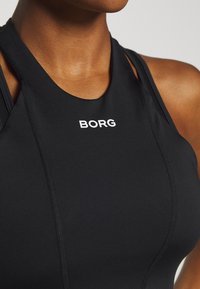 Černý sportovní top bez rukávů s kulatým výstřihem a bílým logem "BORG" na přední straně. Hladká, elastická tkanina se švy.