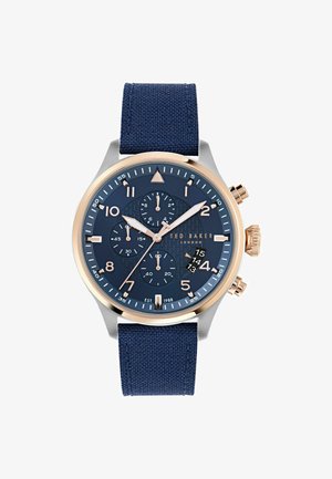 Marineblå stofrem ur med en mørkeblå tekstureret urskive, roseguld detaljer, sølvmetal urkasse og flere chronograph underdialer.