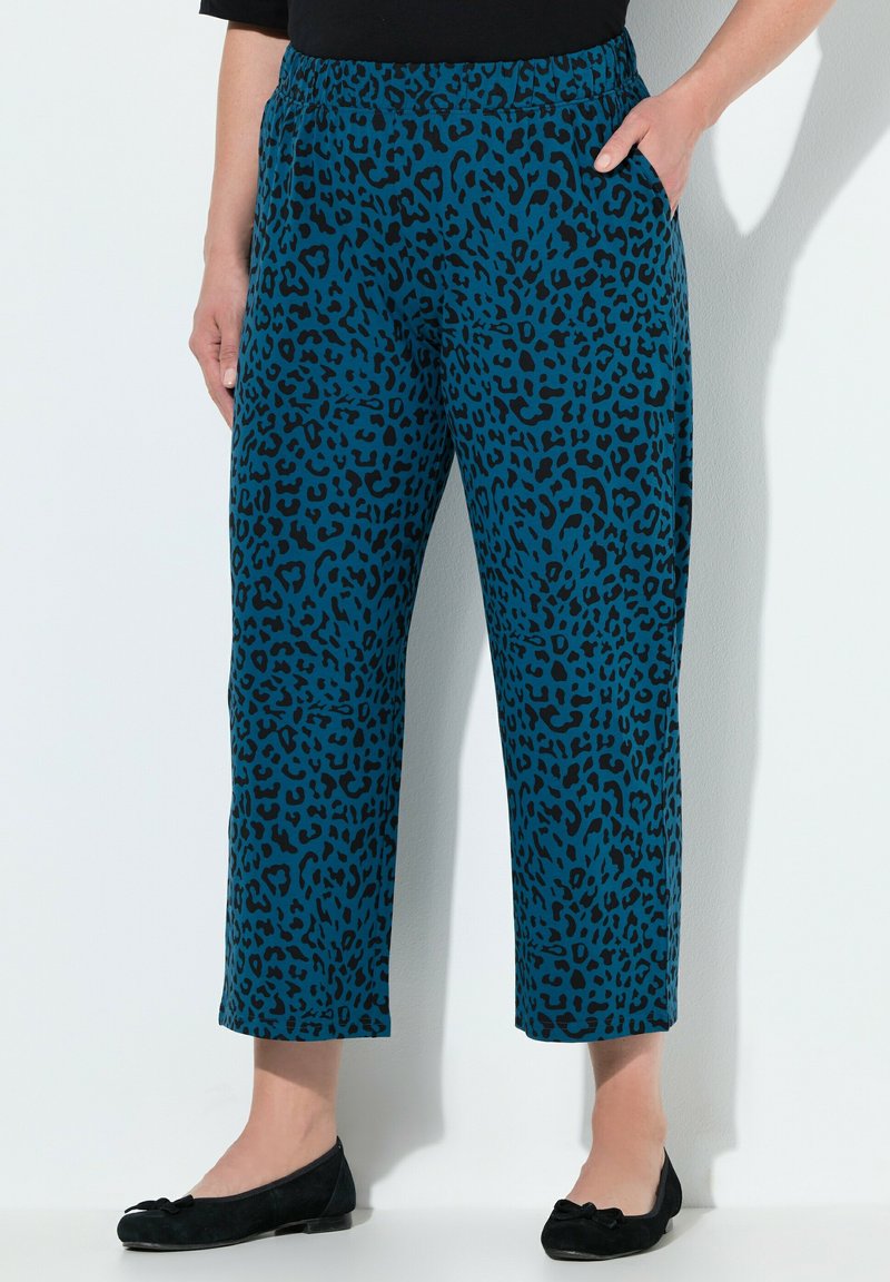 Türkise Leopardenmuster-Hosen mit einem dehnbaren Bund, cropped Länge und Seitentaschen. Kombiniert mit schwarzen Ballerinas und einem schwarzen Oberteil.