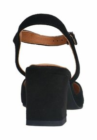 Sandale à talon haut en daim noir avec une bride de cheville, un talon carré et un intérieur en cuir présentant une texture lisse et un matériel minimal.