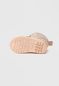 Bota rosa com padrão floral e sola de borracha texturizada. Apresenta um material superior liso e uma alça traseira resistente para facilitar calçar.