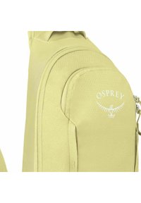 Mochila amarillo-verde con una superficie texturizada, bolsillo frontal con cremallera y logo blanco de Osprey. Presenta correas ajustables y un diseño ergonómico.