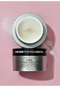 Tarro plateado y negro de crema hidratante con colágeno con tapa transparente. Textura blanca y cremosa visible en el interior. La etiqueta incluye detalles del producto.