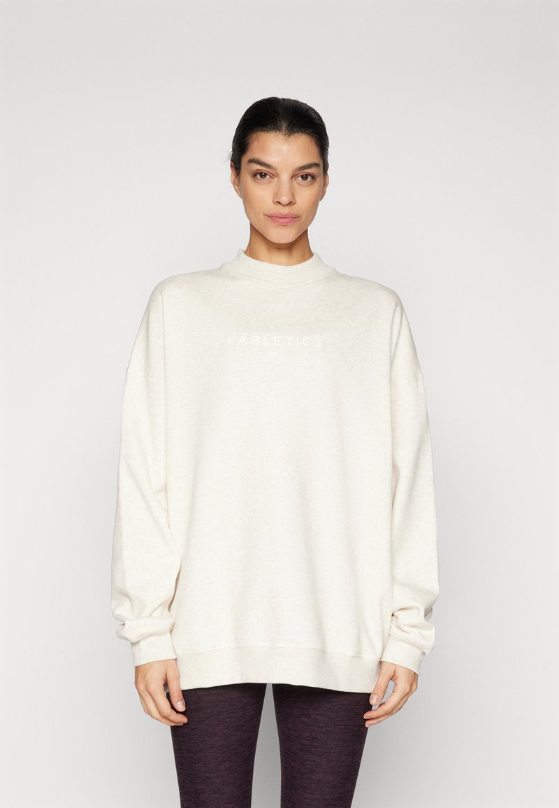 Sudadera de gran tamaño color crema con cuello y puños de canalé, que presenta un logo blanco en el centro. Tejido suave y texturizado.