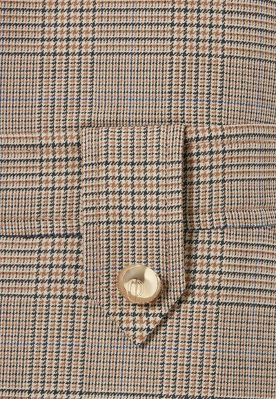 Tela de cuadros beige y marrón con finas líneas azules, con un bolsillo de solapa asegurado por un botón dorado. Patrón de tejido texturizado evidente.