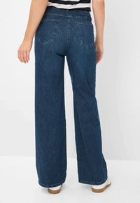 Jeans a gamba larga di colore blu scuro con vita alta, due tasche posteriori e orlo grezzo; realizzati in denim con una superficie leggermente testurizzata.