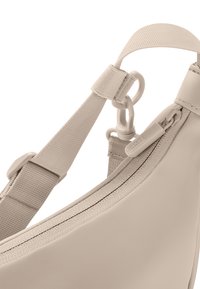 Borsa a tracolla di un beige chiaro con materiale liscio, tracolla regolabile e zip. Presenta un attacco a gancio e dettagli cuciti.