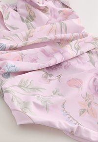 Ljusrosa tyg med mjuka blommönster i pastellfärger; slät textur med flödande veck och diskret glans.