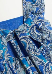 Blaues gemustertes Kleid mit filigranen Paisleymustern in Weiß und Hellblau, mit Rüschendetails und einem glatten, strukturierten Oberteil.