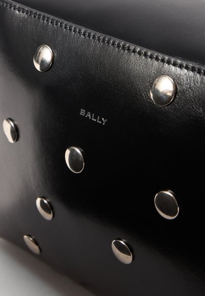 Černá kožená taška s kovovými hroty a embosovaným logem "BALLY". Hladký povrch s precizním prošíváním a metalickými akcenty.
