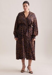 Abito avvolgente con stampa leopardata in marrone e nero, dotato di scollatura a V profonda, maniche lunghe e una cintura coordinata in vita. Tessuto finito liscia.