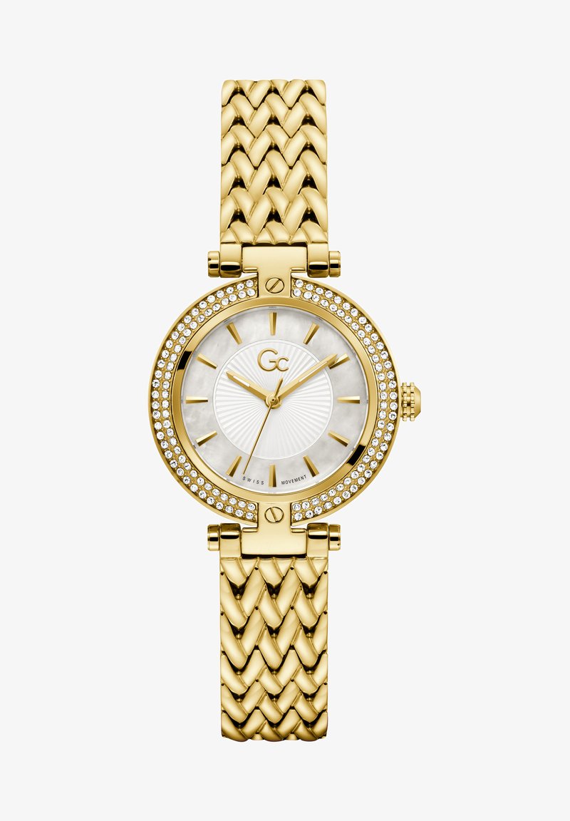 Arany szíjjal és kerek tokkal rendelkező karóra, kristály bevonattal. A fehér számlapon arany mutatók és jelölők találhatók, texturált dizájnnal.