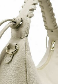 Sac en cuir beige avec une surface texturée, doté d'une poignée tressée, d'accents métalliques dorés et d'une fermeture zip.