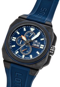 Blå kronografklocka med svart klockhus, texturerad blå silikonarmband, lysande markörer och orangea accenter på visarna och urtavlan.