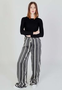 Top lungo a maniche nere con effetto a coste abbinato a pantaloni larghi a righe bianche e nere. I pantaloni presentano una vita con cordino e una texture liscia.