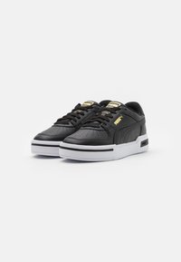 Black leather sneakers with a perforated toe, white sole and black accents. Features gold branding on the tongue and sides.