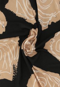 Abstrakcyjna tkanina z wirującymi wzorami w odcieniach beżu i czerni. Materiał ma miękką strukturę, a kontrastujące kolory oraz płynne linie dodają mu charakteru.