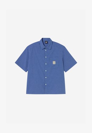 Μπλε πουκάμισο με κοντά μανίκια και μικρό καρό μοτίβο, με τσέπη στο μπροστινό μέρος που φέρει ένα μπεζ τετράγωνο πατς με λογότυπο.