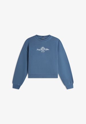 Blå genser med rund hals og lange ermer, med hvit "Tommy Hilfiger Social Club Los Angeles"-logo midt på brystet, ribbestrikkede mansjetter og kant.