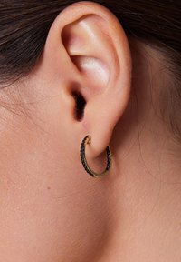 Złota kolczyk w kształcie obręczy z cienkim akcentem ozdobionym małymi czarnymi koralikami, prezentująca gładką teksturę i okrągły kształt.