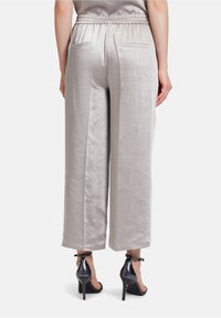 Ljusgrå satinkvadratbyxor med elastisk midja, med två bakfickor och en mjuk yta. Tillsammans med svarta klacksandaler.