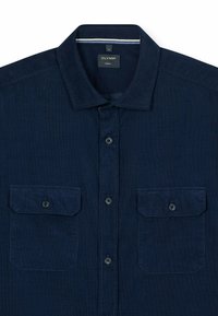 Marineblaue Button-up-Bluse mit spitzem Kragen, zwei Fronttaschen und strukturierter Oberfläche. Verfügt über dunkle Knöpfe und kontrastierende Nähte.