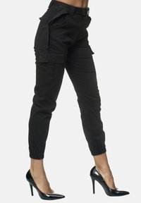 Svarta cargobyxor med slim fit, elastiska mudd och flera fickor. Matchas med blanka svarta stilettklackar för kontrast.
