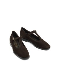 Brązowe zamszowe buty T-strap z ostrym noskiem, z małą klamrą i niskim obcasem. Gładka wewnętrzna podszewka i minimalistyczne zdobienia.