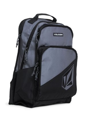 Szary i czarny plecak Volcom z wieloma zapinanymi na suwak przegródkami, górnym uchwytem i przednią naszywką z logo.