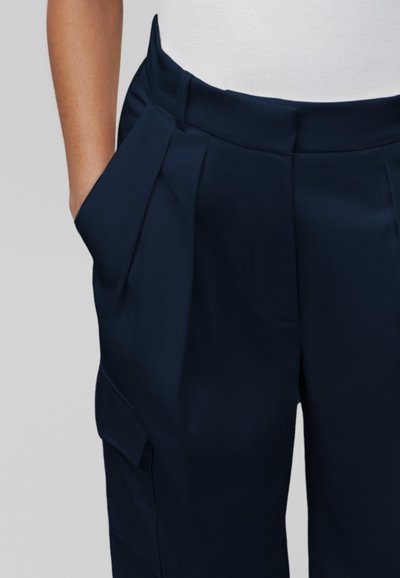 Donkerblauwe geplooide broeken met een brede tailleband en zijzakken, gemaakt van een zachte, op maat gemaakte stof.