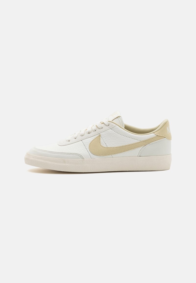 Bílé kožené tenisky s světle béžovými akcenty, strukturovaný svršek, šněrování a polstrovaný límec; mají charakteristické logo swoosh.
