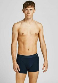 Nachtblaue Boxershorts aus glattem Material, mit elastischem Bund, der den Markennamen trägt, und einer taillierten Passform, präsentiert an einem männlichen Modell.