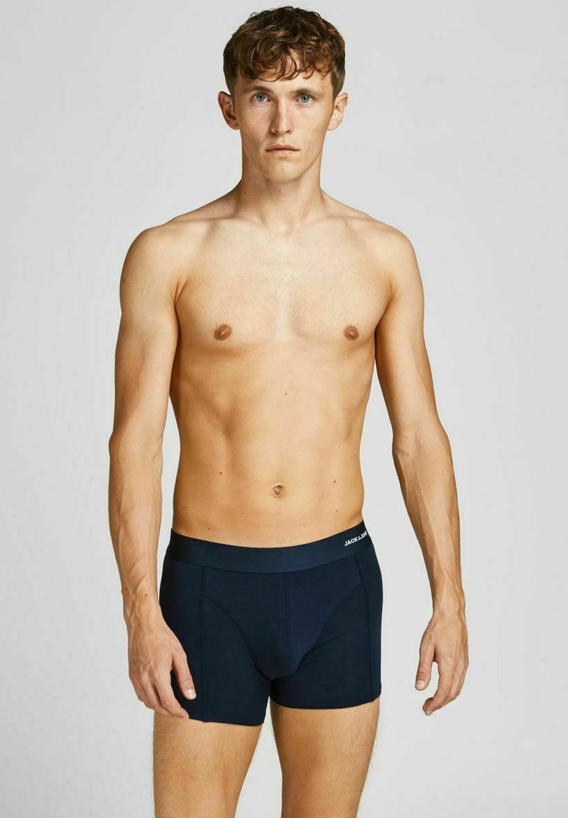 Nachtblaue Boxershorts aus glattem Material, mit elastischem Bund, der den Markennamen trägt, und einer taillierten Passform, präsentiert an einem männlichen Modell.