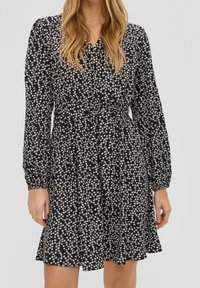 Černé květinové šaty s nařaseným pasem, dlouhými nabíranými rukávy a malým vzorem bílých květin. Volná sukně se mírně rozšířeným lemem.