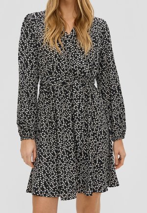 Robe noire à motifs floraux, avec une taille froncée, de longues manches bouffantes et un petit motif de fleurs blanches. Jupe fluide avec un ourlet légèrement évasé.