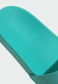 Sandalo slide Adidas turchese con tomaia testurizzata, caratterizzato da un logo in rilievo e accenti traforati sui lati.