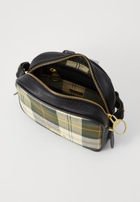 Bolsa de couro preta com um padrão xadrez em creme, verde e laranja. Possui um fecho de correr dourado e um bolso interno com fecho.