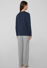 Námořnický dlouhý rukáv s kulatým výstřihem, spárovaný se světle šedými širokými kalhotami. Měkká textura a volný střih pro pohodlí.