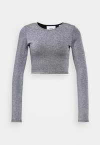 Långärmad, glittrig silverfärgad cropped topp med rund halsringning mot en vit bakgrund.