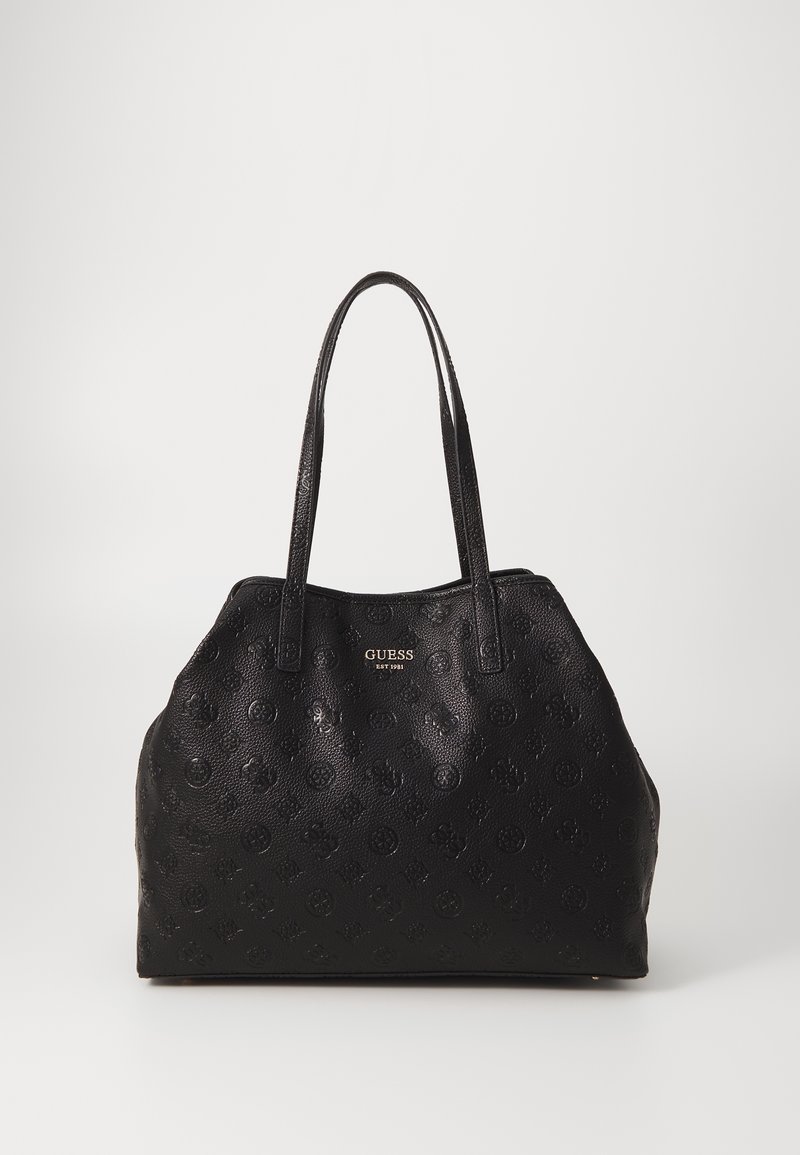 Sac à main Guess en cuir texturé noir avec doubles anses et logo doré à l'avant sur fond uni.