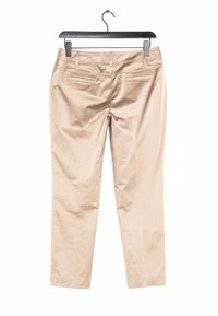 Béžové bavlněné kalhoty s úzkým střihem, s hladkým povrchem, rovnými nohavicemi a zadními kapsami. Zavěšené na černém ramínku.