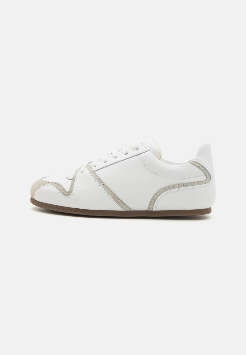 Zapatilla blanca con acentos de ante; cuenta con una punta redondeada, suela plana y seis ojales. Diseño limpio con un sutil detalle de costura.