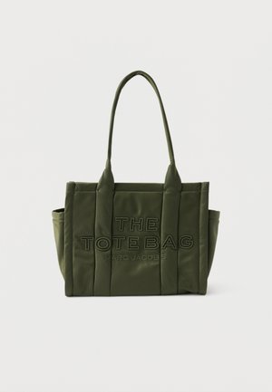 Oljčno zelena oblazinjena torba z dvema dolgima ročajema in vtisnjenim napisom "THE TOTE BAG MARC JACOBS" na sprednji plošči.