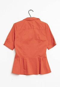 Top peplum de tejido naranja con cuello con solapa, mangas cortas y dobladillo acampanado. Textura suave con un corsé ajustado.