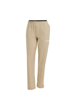Pantalons de sport beiges en tissu lisse et léger, avec une taille élastique et un logo blanc sur la jambe gauche.
